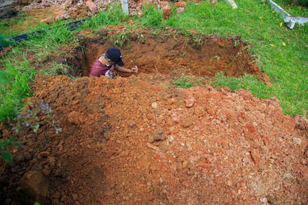 Kedah, Malaysia -May 20, 2021: A man making a grave for funeral at Muslim cemetery.のeditorial素材