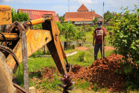 Kedah, Malaysia -May 20, 2021: A man making a grave for funeral at Muslim cemetery.のeditorial素材