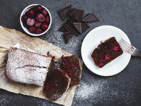Chocolate cake on baking paper with cherry and pieces of chocolateの写真素材
