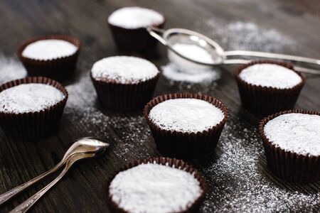 Chocolate cupcakes with powdered sugar  on wooden tableの写真素材