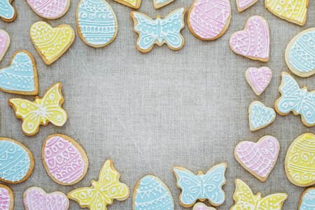 Frame of colorful homemade Easter cookies on linen tableclothの写真素材