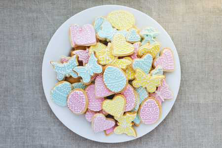 Colorful Easter cookies on white plate on linen tableclothの写真素材