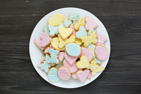 Colorful Easter cookies on white plate on dark gray wooden tableの写真素材