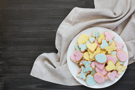 Colorful Easter cookies on white plate on dark gray wooden tableの写真素材