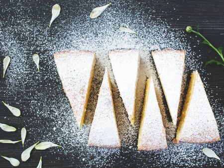Pieces of lemon pie on wooden table with sugar powder
