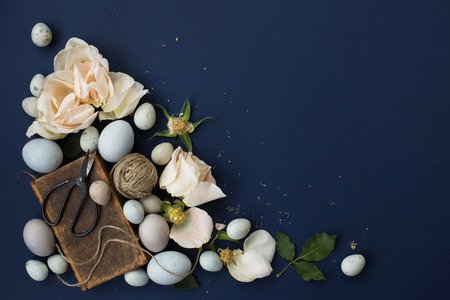 Easter background with blue colored eggs, books and roses on blue background. Top view