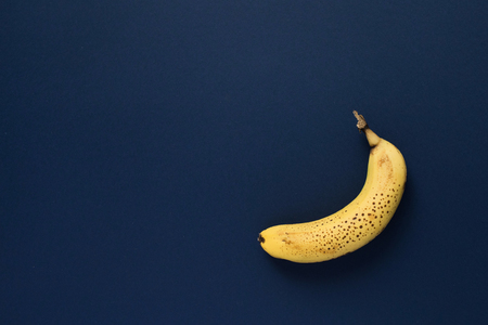 One ripe spotted banana on dark blue background. Top viewの写真素材
