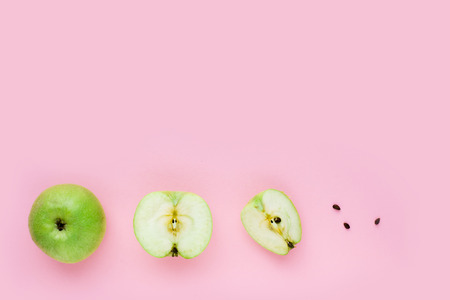 Green apple, half apple and quarter apple on pink backgroundの写真素材