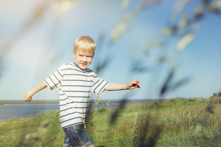 Blond boy joyful and running on nature.の写真素材