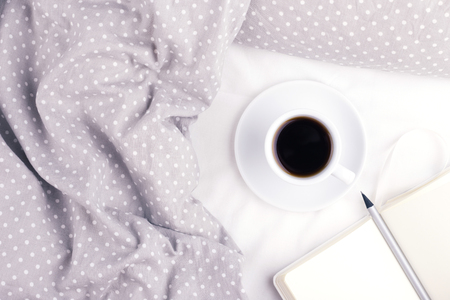 The cup of coffee and paper notebook on bed.の写真素材