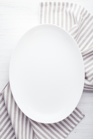 Empty white oval plate on wooden tableの写真素材
