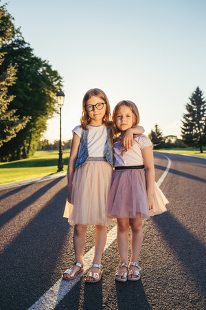 Two girls standing on the froad and hugging.の写真素材