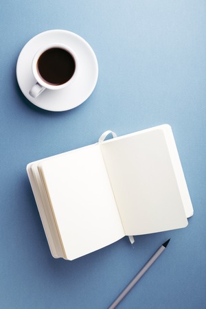 A cup of coffee and notebook on the table.の写真素材