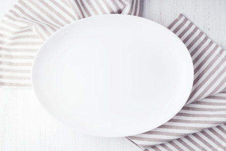 Empty white oval plate on wooden tableの写真素材