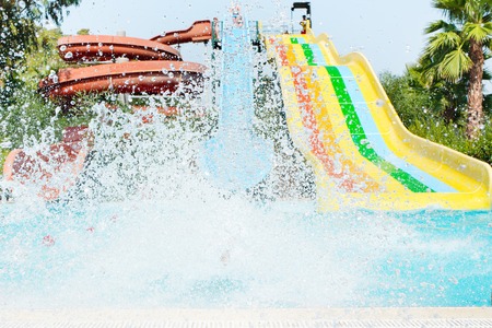 Kid going down the hill in the aqua park. Splashes of water.の写真素材