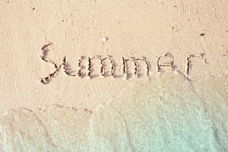 Word Summer written in the sea sand. Waves washed away the inscription.の写真素材