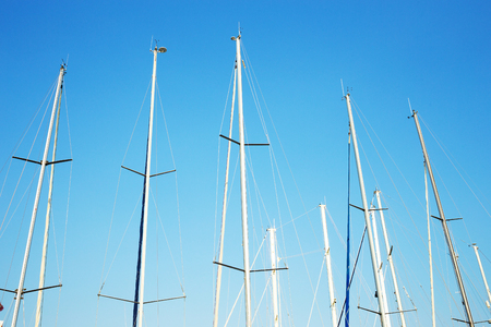 Many yacht masts against the blue sky. Marine concept.