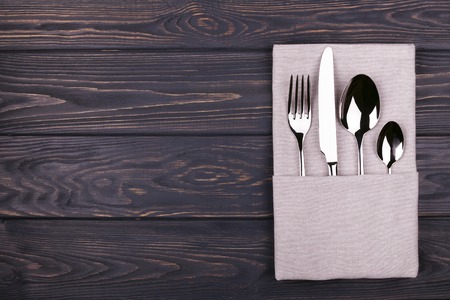 Set of fork, spoon, teaspoon and knife with linen napkin on wooden table. Top view.の写真素材