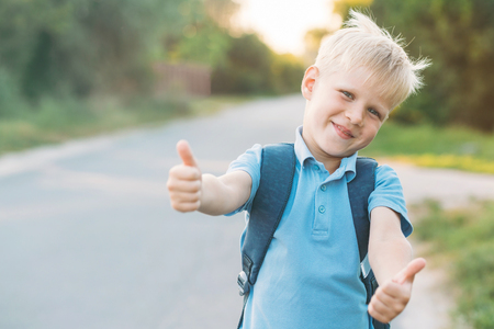 Cheerful boy staying on the sidelines and gives a thumbs-up. Schoolboy likes education.の写真素材
