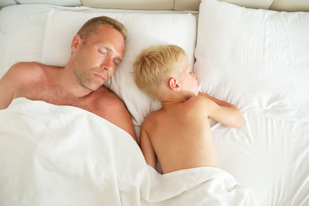 Father and son sleeping on white pillow. Sweet dream concept. Top view.の写真素材