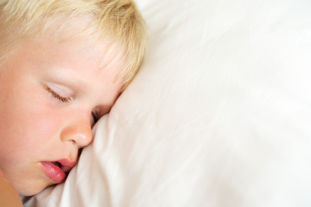 Blondy little boy sleeping on white pillow. Sweet dream concept. Top view.の写真素材