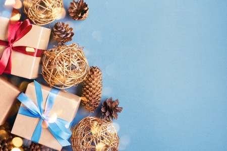 Christmas background with gift boxes and cones on blue background. Gift boxes tied with red and blue...