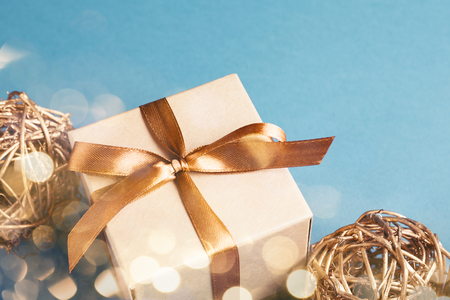 Christmas gift box with golden decorations on blue bacground. Gift box tied with golden ribbon. Holiday greeting card.の写真素材