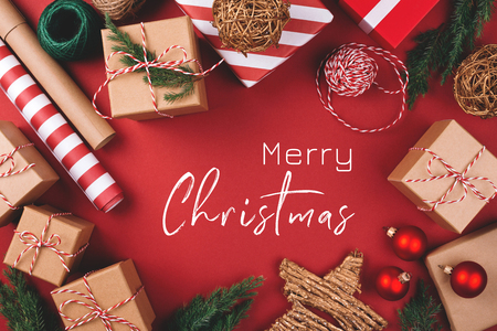 Christmas greeting card. Background with gift boxes, clews of rope, papers rools and decorations on red. Preparation for holidays. Top view.の写真素材