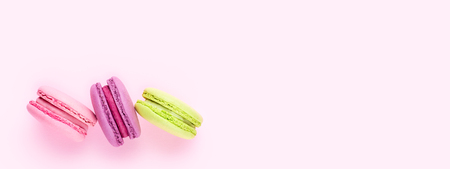 Three colorful macaron cookies on pink background. Top view, minimal design.の写真素材