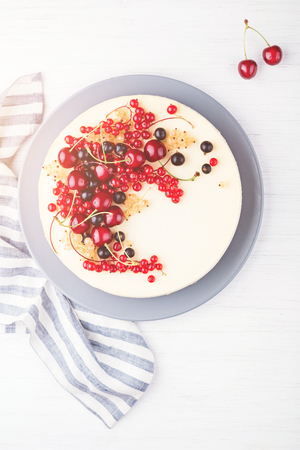 New York cheesecake with berries on white wooden table and napkin. Top view. Red currant, black currant and cherry.の写真素材