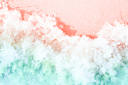 Soft waves with foam on sandy beach toned in trendy colors of the year 2019. Living Coral and Limpet Shell.の写真素材