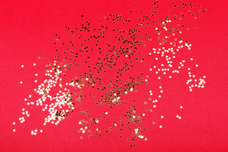 Golden star confetti on red background. Christmas and holiday decorations.の写真素材