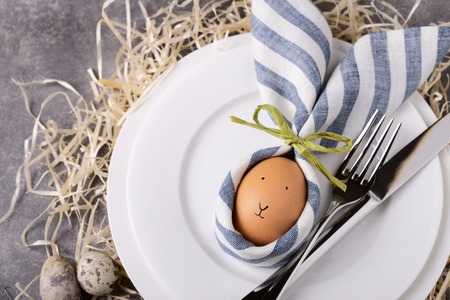 Beautiful Easter table setting with egg in napkin Easter Bunny. Top view, close up.の写真素材