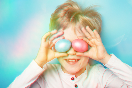 Boy holding Easter eggs in front of his eyes with 3D effect. Easter mood.の写真素材