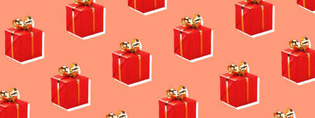 Red gift boxes with golden bow on trendy background. Minimal styled Christmas and holiday concept. Banner for website.の写真素材