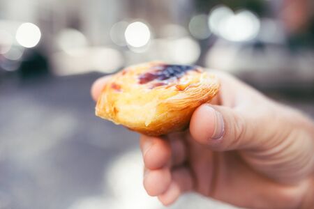 Traditional portuguese dessert in mans hand. Pastel de Nata.の写真素材