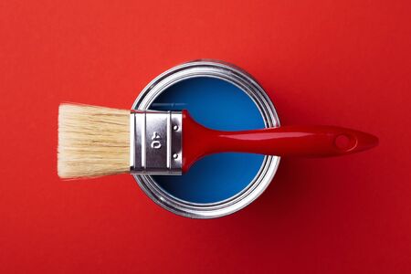 Can of classic blue paint with brush on red background. Top view.の写真素材
