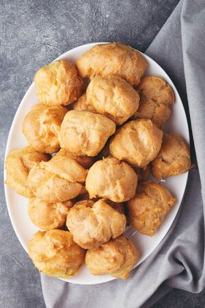 Top view on profitroles on white plate on stone table with napkin. Traditional french dessert.の写真素材