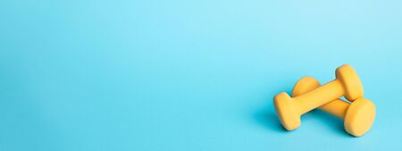 Banner with two yellow dumbbells on blue background with copy space. Sport and fitness.の写真素材