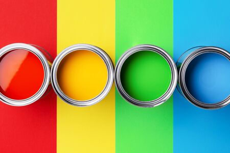 Row of cans of colorful paint on colorful background. Top view on red, yellow, green and blue paints.の写真素材