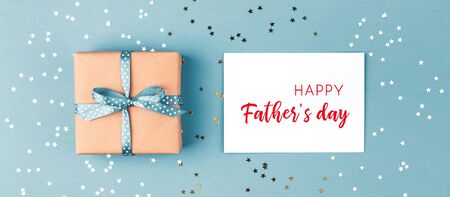 Gift box tied blue ribbon and Happy Fathers day greeting card on blue