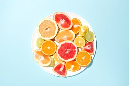 Plate with mix of citrus fruits on blue background.の写真素材