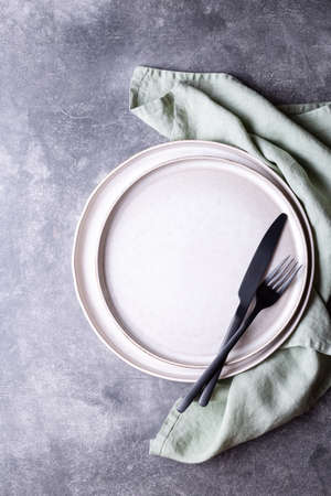 Plates, black cutlery and linen napkin on stone table. Setting table, top view.の写真素材