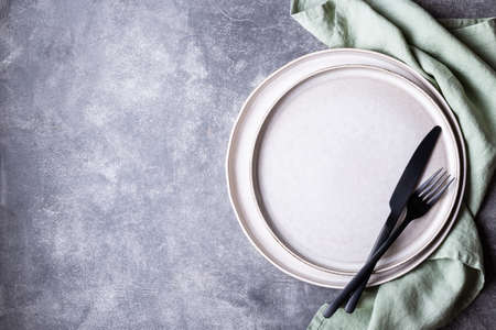 Plates, black cutlery and linen napkin on stone table. Setting table, top view.の写真素材