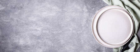 Banner with plates, black cutlery and linen napkin on stone table. Setting table with copy space in natural colours, top view.の写真素材