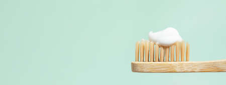 Banner with bamboo toothbrush with toothpaste on mint background with copy space. Close up view in sunlight.の写真素材
