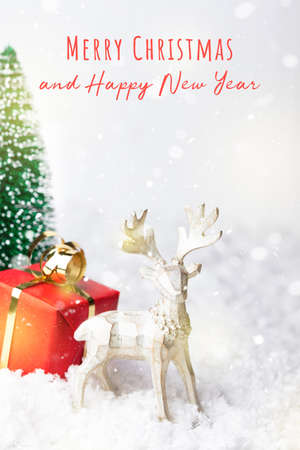 Snowy Christmas greeting card with congratulation inscription. Reindeer and red gift box.の写真素材
