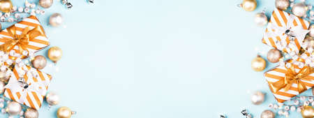Banner with Christmas composition with gift boxes and golden decorations on blue background. Flat lay, greeting card.の写真素材