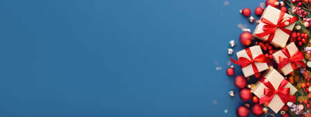 Christmas border with gifts, evergreen branches and red decorations on blue background. Banner for website.の写真素材