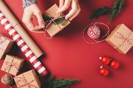 Christmas background with gift boxes and decorations on red. Preparation for holidays. Top view with copy space. Womans hands holding gift box.の写真素材